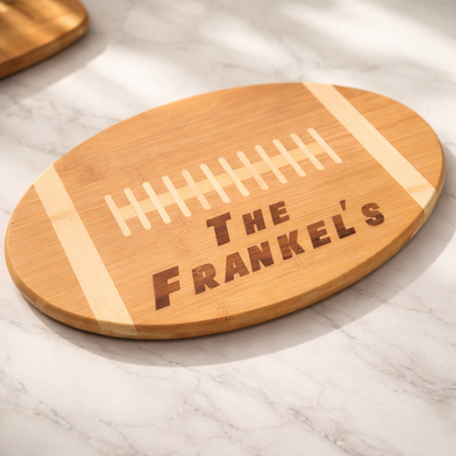 Wooden football-shaped cutting board with 'The Frankel's' engraving on a marble surface