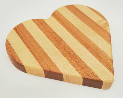 Heart-shaped wooden cutting board with striped pattern on a white background