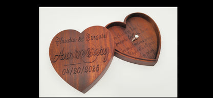 Wooden heart-shaped box engraved with 'Anniversary' and a ring inside on a white background