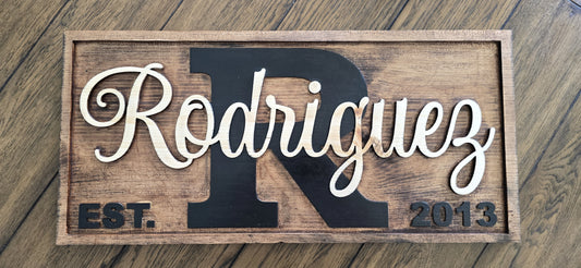 Wooden sign with 'Rodriguez' and 'R' on a wooden surface