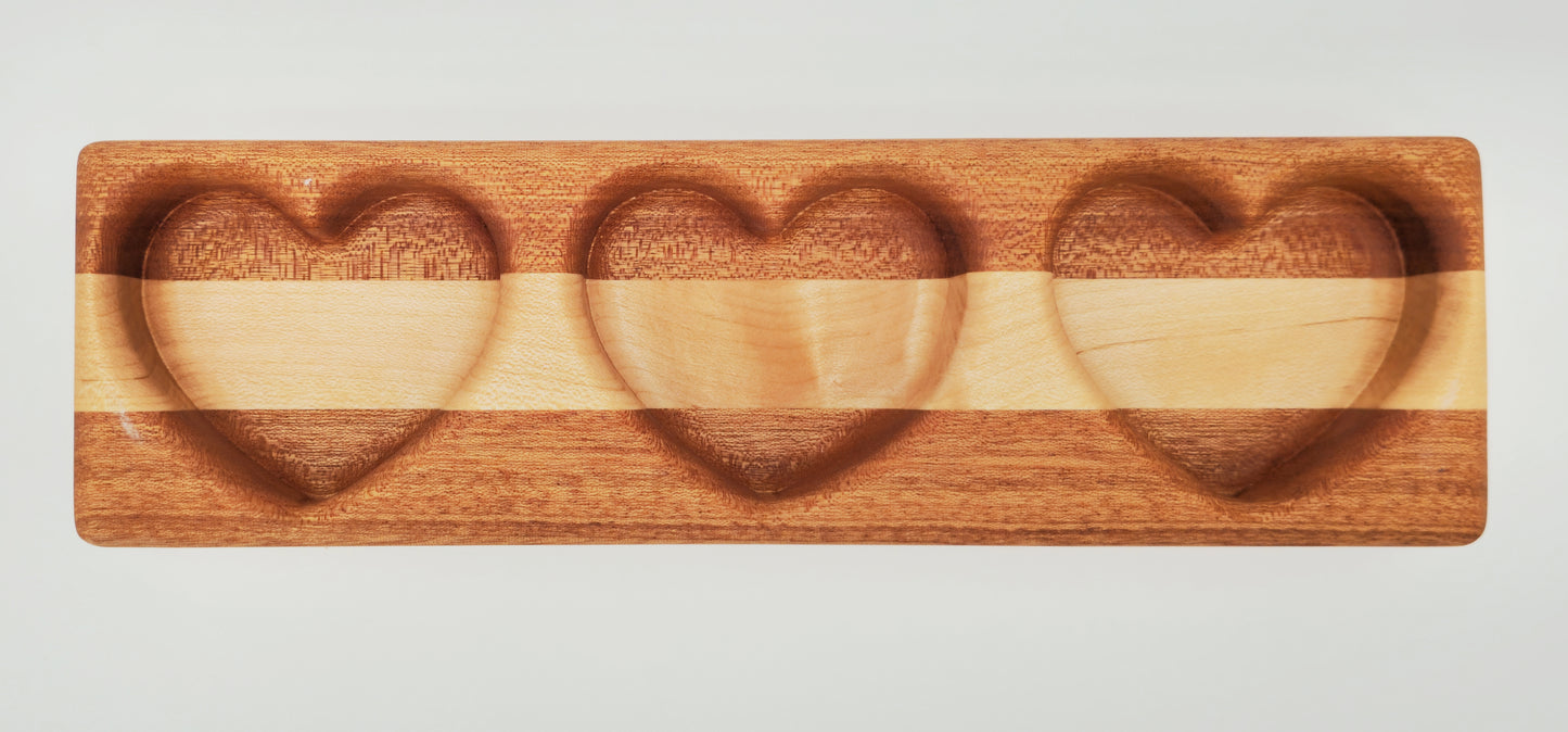 Wooden tray with three heart-shaped compartments on a light gray background